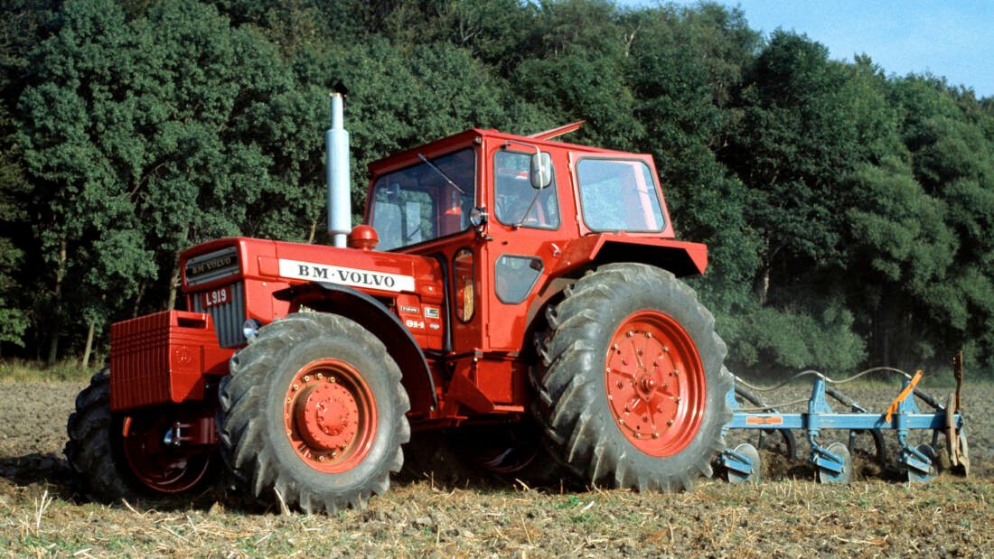 Saints are very much in the mind in terms of Ireland’s patron saint, but it is worth remembering another fellow who set out from Britain to Sweden in a similar bid to spread the the word of christianity. His name was Eskil and he set out east 700 years after St. Patrick crossed the water to Ireland. Although known to be born in Britain, his early childhood is something of a mystery. An unhappy ending However, by various ways and means he arrived as a missionary in central Sweden and settled at a village then called Tuna, sometime around 1080, where he set about converting the pagans to christianity. Despite some success in this endeavour, not all the locals were impressed, especially when he interrupted a ritual sacrifice, causing the said pagans to rapidly despatch him with axe and stones. Bridge at Eskilstuna Munktell Sweden The river at Eskilstuna today. The bridge was built in the Munktell works Whether this gruesome ending was a political move initiated by the then King of Sweden is a matter of some uncertainty. What is known is that he was buried near the location of his death some 15 miles from the city that now bears his name, a funeral prompted by the gushing of a fresh spring where his body was laid for a rest during the journey back to Tuna. That small village later adopted his name as a prefix and grew to become the city of Eskilstuna, and it is here that there lies another spiritual home, that of Volvo Construction. Creeping industrialisation in Sweden The area around Eskilstuna was blessed with modest iron core deposits and, along with coke produced from the surrounding forests, ironworks were established using the natural fall of the river to power metal working hammers. From these humble origins a town grew that specialised in forging steel goods, eventually, these included weapons, especially rifles, which were produced there from 1812 onwards in a royal armoury built for the task. Rifle factory Eskilstuna The old rifle factory is now a museum celebrating Eskilstuna’s industrial past The geographical location, far away from the coast and invading armies, was another attractive feature as it would take a long time for invading armies to capture it, during which period it could continue supplying the home side. A second saviour Reliance on water power had the drawback of necessitating many small workshops rather than a central workshop, as factories could only be located where there was a fall in the river and wheel could be installed. Munktell tractor volvo Munktell’s first tractor was the 30-40, of which this fully restored example at the Munktell Museum is the only known survivor Yet, by all accounts, manufacture thrived in the area and it was to this hub of activity that a young and hugely talented engineer by the name of Theofron Munktell was drawn. Munktell had been responsible for upgrading the royal mint in Stockholm and much of the equipment on which it ran during the early part of the 19th century was designed and built under his supervision. Theofron Munktell Eskilstuna, Sweden A statue of Theofron Munktell sits outside the Munktells Museum His first assignment was with the Royal armoury and from there he started his own engineering business, which at first, comprised the manufacture of book printing presses. His company rapidly grew and would go on to encompass mining equipment, threshers, steam engines and even the first railway locomotive made in Sweden, the Forstlingen. The first tractors Tractor production commenced in 1913 with the Munktell 30-40, a large machine modelled on the American prairie ploughing tugs of the time, designed for large estates rather than local farms. Munktell clearing forests and rocks A Munktell 20-24 is seen here clearing boulders from fields. They were first produced in 2017 Further, smaller models followed, as did a marriage of convenience with another engineering company, Bolinder, which was famed for its boat engines. The two companies shared the same bank and it was this institution that brought them together as Bolinder Munktell (BM) and established their base at Eskilstuna. Elsewhere in Sweden The second world war saw a drastic shortage of raw material, especially rubber, hampering the fortunes of a younger Swedish company which had built its business on building cars trucks and buses. Volvo car factory SKF Sweden Volvo car production in the 1920s The company was called Volvo, a name which comes from the Latin of ‘I roll’. This gives a clue as to its parentage and source of capital – the bearing company SKF. The founder of SKF was Sven Wingqvist, inventor of the self aligning ball bearing, a development which had brought him a significant fortune. Although never a subsidiary of SKF, Volvo was initially financed by WingqvistIt himself. It struggled with sales of its first car, built in 1927, but a truck, introduced the following year, was such a success that it allowed the company to later buy up its engine supplier, Pentaverken, to create Volvo Penta. Running out of rubber Throughout the 1930s, the company expanded due to its engine and vehicle manufacture, the latter requiring rubber for their tyres. Unfortunately, other countries had a stronger call on the world’s rubber supplies at the time, necessitating a rethink on what it was possible to produce. Tractors of the time ran on steel wheels and although Volvo had never made a tractor before, it had supplied a six-cylinder engine to BM earlier in the war for its tractor range. Tractors were obviously a vehicle it could continue to produce so in 1943, it started buying transmissions from BM for the first Volvo tractor, the T. Volvo T41 tractor in Sweden Volvo’s first tractor was the T41. It had a Bolinder Munktell transmission and Volvo’s own Hesselmen engine Cooperation between the two companies continued until 1950 when the banks once again stepped in and merged them to form BM Volvo. Although tractor production was concentrated in Eskilstuna, they at first competed on the market as two separate brands, but gradually the operation was streamlined until, in 1973, the tractors were sold only in red under the rearranged name of Volvo BM. Ground speed PTO points to pastures new Forestry, construction and military requirements, as well as agriculture, played a large part in the company’s fortunes and the tractors were engineered with ground speed PTO. Volvo army pto Like its forerunners, this ex army Volvo BM 650 from Sweden has no lift linkage, just a NATO coupling and live PTO This feature enabled them to be coupled to a powered trailer, creating a 6×4 vehicle which met the army’s requirement for rapid transport through the Nordic forests whatever the season. It wasn’t just the army that took advantage of this ability, it also came to prominence in the mid 1960s when Volvo created a four-wheel-drive articulated dump truck from its Boxer 350 skid unit and a trailer bolted directly onto the rear. Volvo trailer boxer 350 Sweden The company’s first articulated dump truck, known as gravel Charlie, was introduced in 1966,. Note the ‘trailer tyres’ at the rear. When joined like this, the two halves became one vehicle and although it was underpowered by today’s standards, sporting just 65hp, it became a great success for the company. This was the birth of Volvo construction and it was just 12 years later that Volvo decided to abandon agricultural machinery altogether and hand over its tractor production to Valmet in Finland, while it concentrated on construction equipment. Nordic tractor valmet volvo The Nordic tractor was a joint development between Volvo and Valmet. Volvo then passed on its tractor business to Valmet This process was completed in 1985 with the last two models built at Eskilstuna being the Volvo BM 2005 and its turbocharged sibling, the Volvo 2105. The works then closed, although the buildings still exist and are used for a variety of purposes, including a community centre. A new dawn for Volvo On reflection it was a wise move, there had been a massive post-war impetus to mechanise the land and within 30 years that had been achieved. Farmers had not only adopted the tractor but had appreciated it could do far more work with a lot less labour, hence tractors got bigger, and so fewer, meaning that volume production declined. Volvos saints Eskilstuna Although Volvo no longer makes tractors, the company still produces timber handling equipment There simply wasn’t the need for the production capacity available within the industry. Volvo managed to get out in time and concentrate on alternative markets, others were not so lucky and many familiar names faded from the scene. St. Eskil is not forgotten in his adopted land, nor is the city’s industrial legacy. The original gun factory is now a museum while the tractor assembly buildings still stand by the river that gave birth to the city. Volvo still has a factory close to Eskilstuna for the production of transmission components, where it continues with research into alternative drive methods. There is also a demonstration and training facility, between the two, the company employs 2,100 people in the city of its birth.