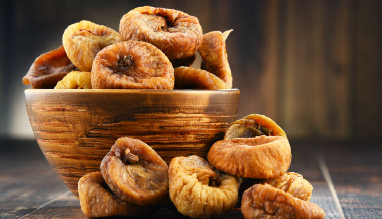 Composition with bowl of dried figs on wooden table