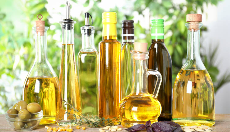 Different sorts of cooking oil in bottles on wooden table